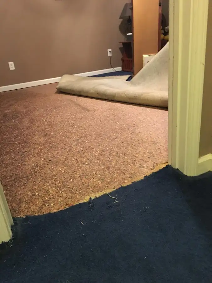 Carpet pad removal revealing water damage during Water Mitigation Services in McPherson